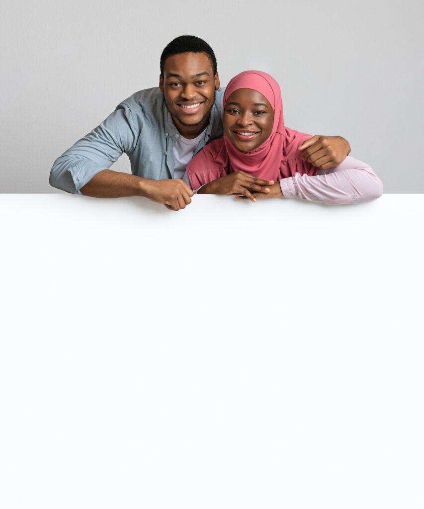 Cute african american couple leaning on white empty board