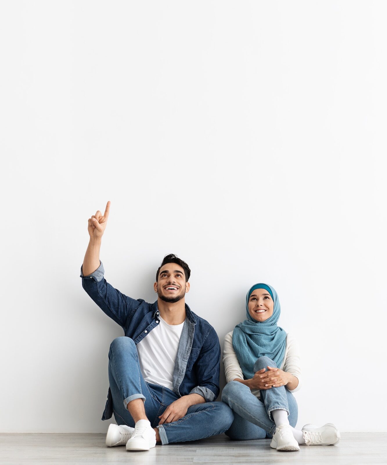 Cute muslim couple looking at empty space on white